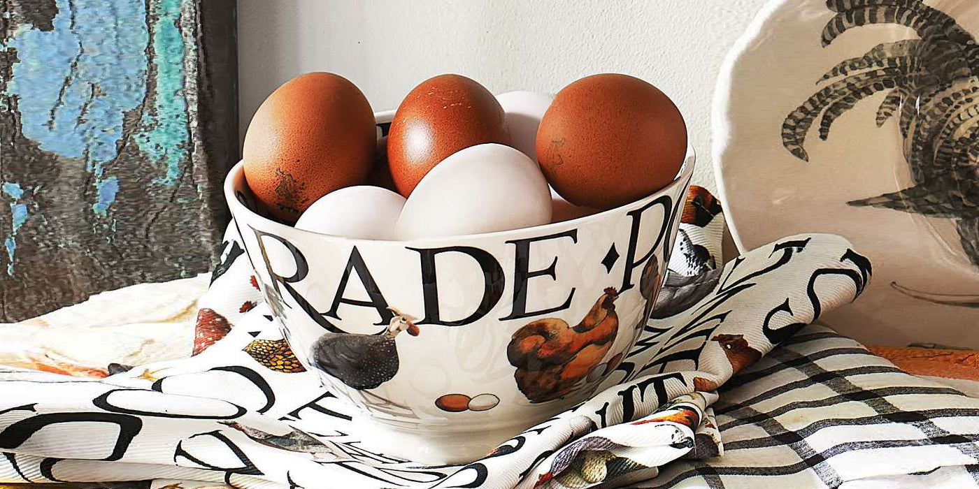 Eggs placed in a large, decorative ceramic bowl by Emma Bridgewater with a dark blue, paint splatter as a design. Part of the ceramic serving platters and bowls collection featuring unique hand painted designs.